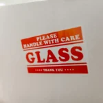 Label peringatan "Handle with Care" pada kemasan pengiriman barang berbahaya